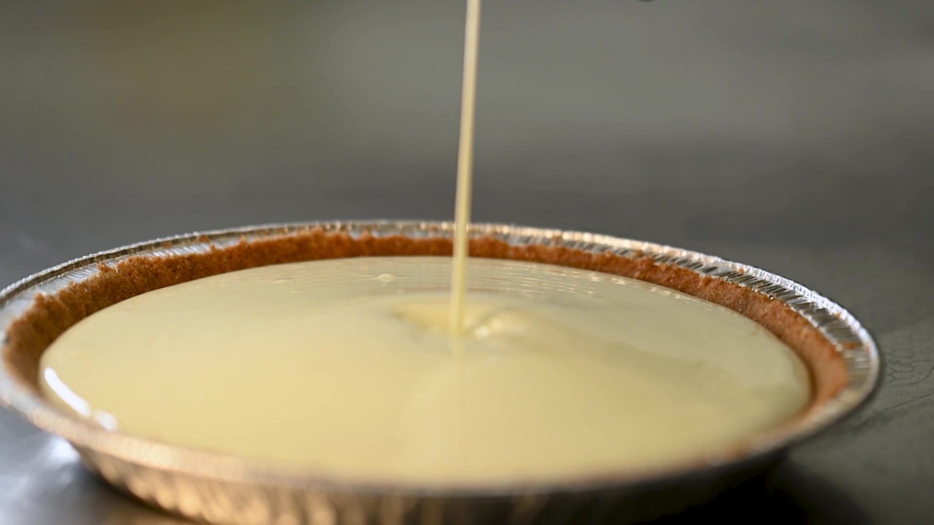 Key lime pie being filled in a graham cracker crust